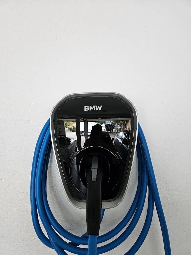 BMW electric vehicle charging station with blue cable on a white wall.