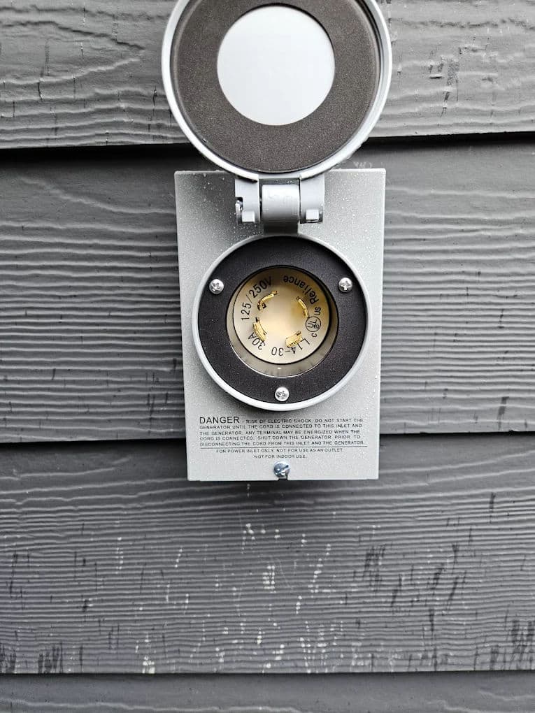 Electrical meter mounted on a gray wall, showing voltage and warning information.