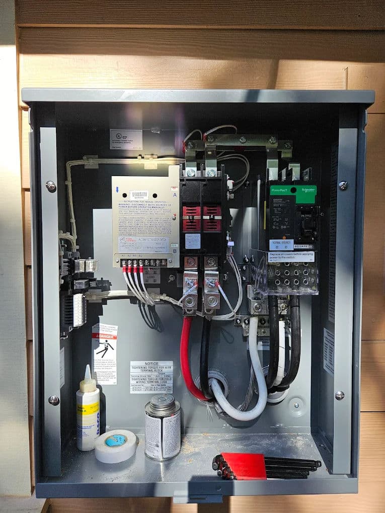 Electrical panel with circuit breakers, wires, and components for power distribution.