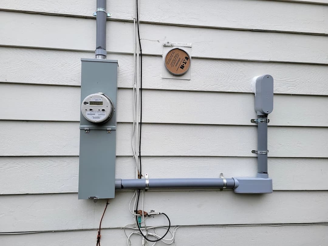 Electric meter and gas line installation on exterior wall of a home.